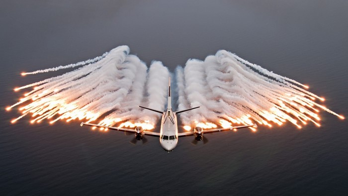 Airplane releasing flares over water