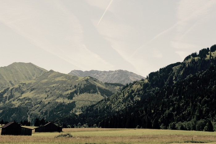 Green mountains and fields with dark wooden sheds