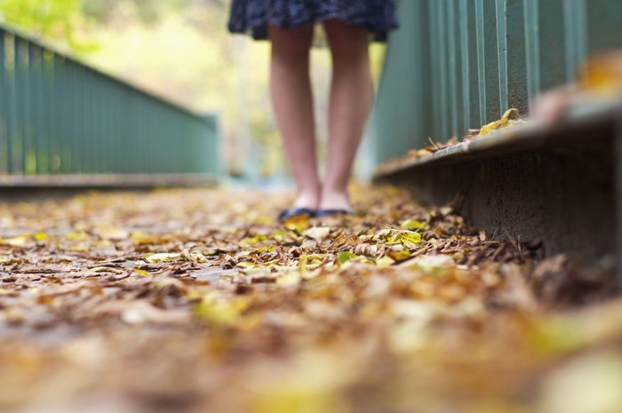 Woman standing on a path covered in autumn leaves