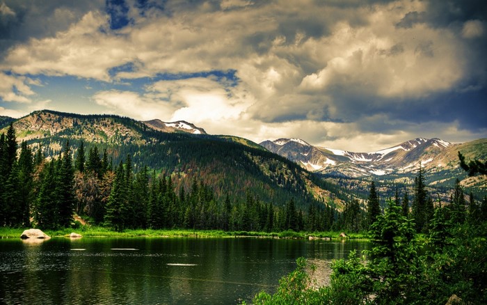 Mountain lake with pine forest and snow-capped peaks