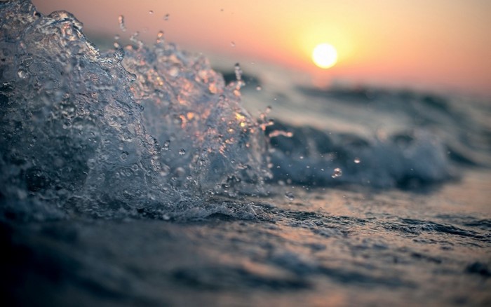 Close-up of a wave crashing at sunset