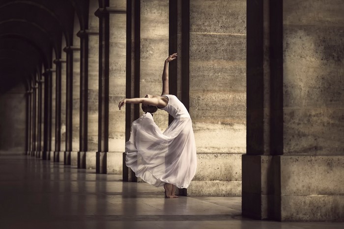 Ballerina dancing in an arched stone corridor