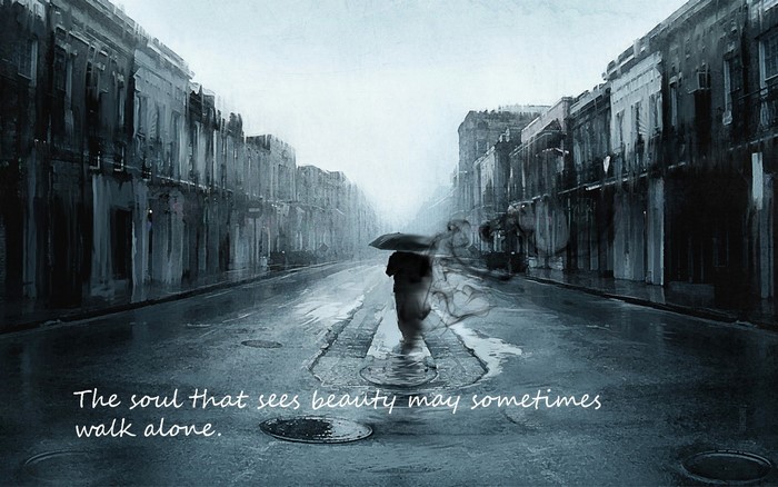 Monochrome street scene with a lone figure under an umbrella