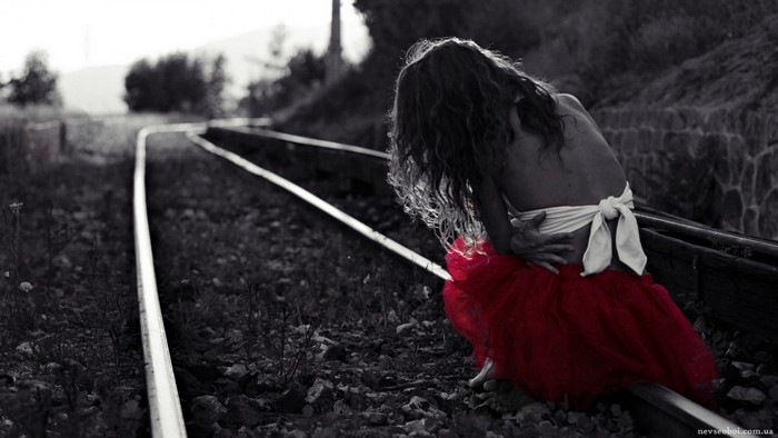 Woman in red skirt on railway tracks