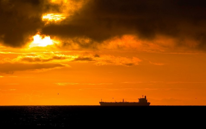 Ship silhouetted against a dramatic sunset over the ocean