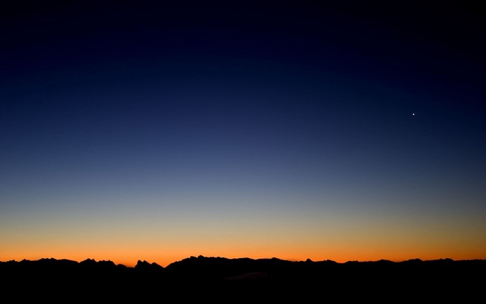 Silhouette of mountains against a twilight sky with a bright star