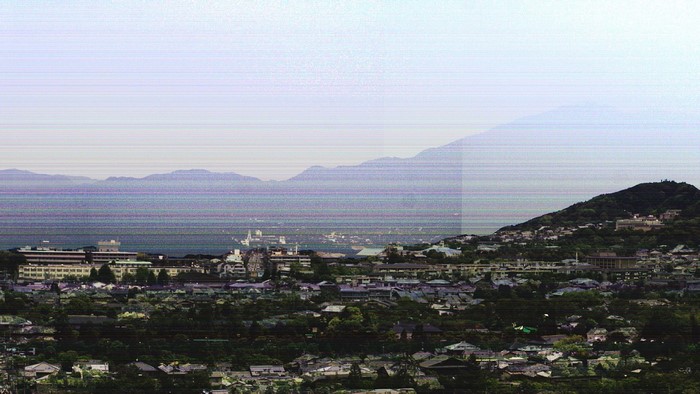 Cityscape with mountains and sea under a hazy sky