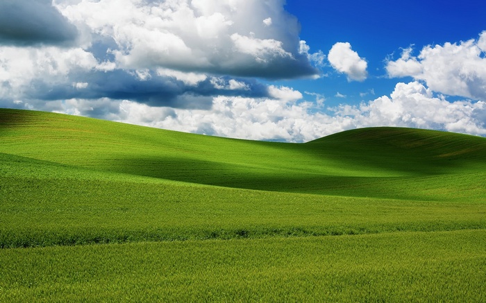 Rolling green hills under a cloudy blue sky
