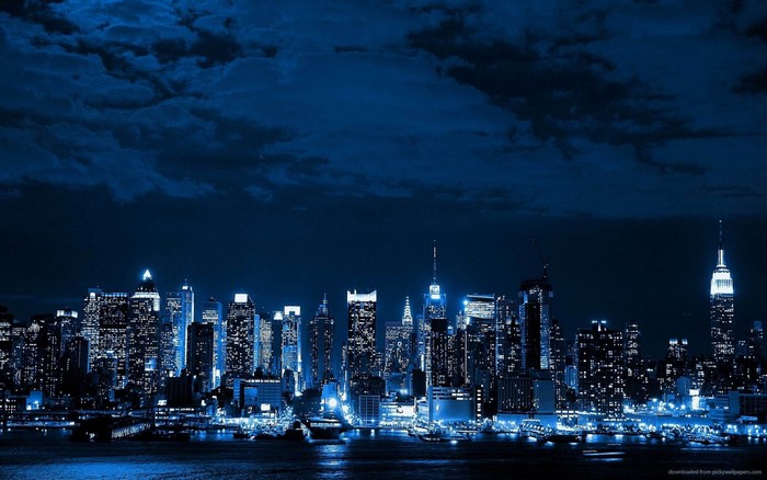 Blue toned cityscape at night with skyscrapers and clouds