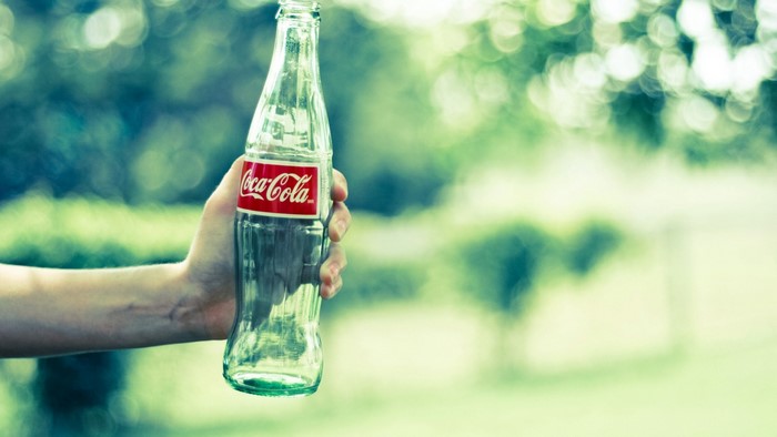 Hand holding a Coca-Cola bottle outdoors