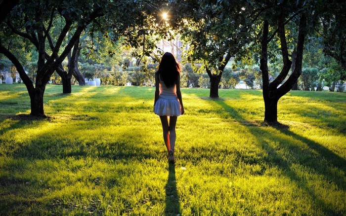 Woman walking in a sunlit park with trees