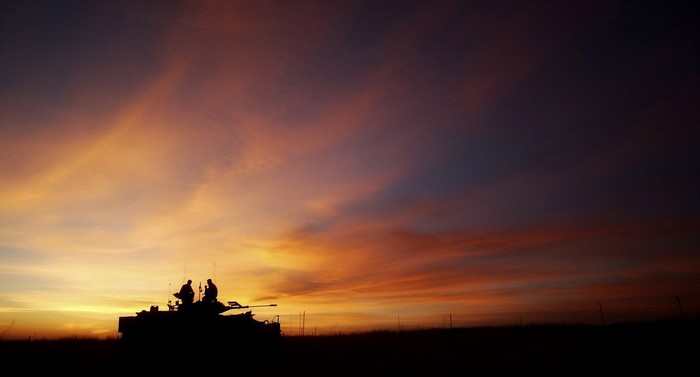 Silhouette of soldiers on an armored vehicle at sunset