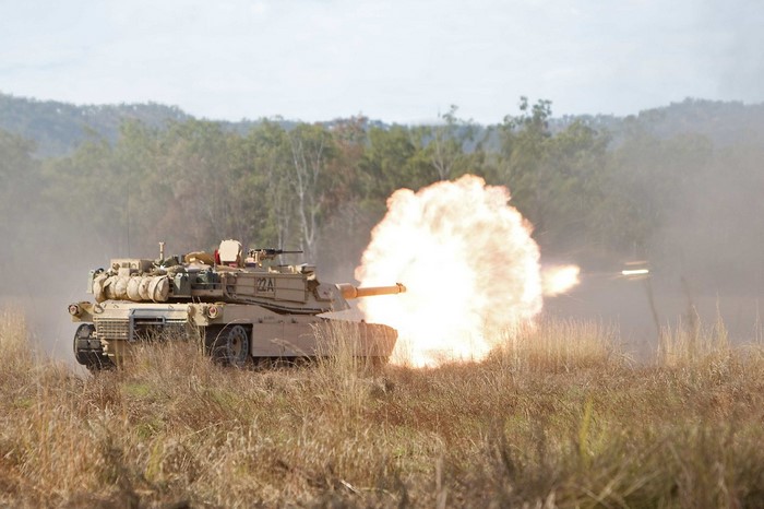 M1 Abrams tank firing a weapon in a field
