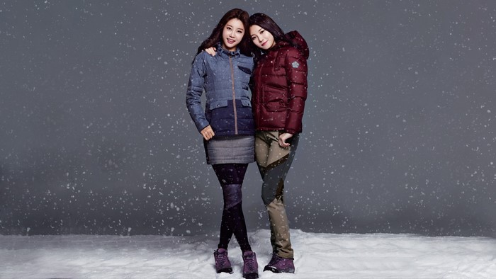 Two women in winter fashion posing in snow