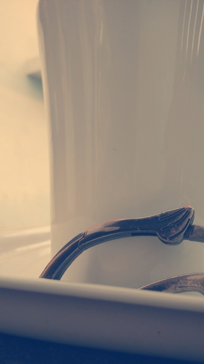 Close up of a white mug with a metal handle