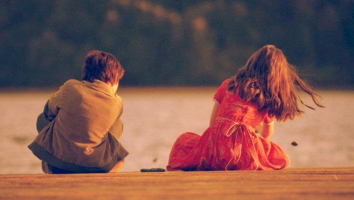 Boy and girl sitting on a dock