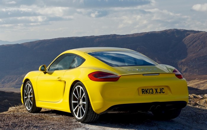 Yellow Porsche Cayman parked on a rocky hill