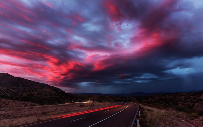 Dramatic sunset over a desert highway with light trails