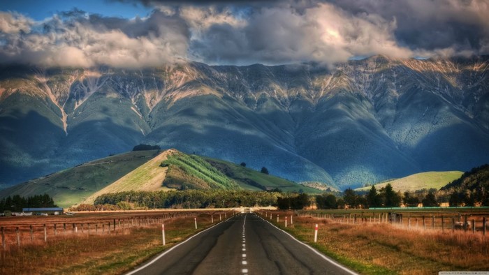 Sunlit Road Leading to Mountain Range in New Zealand