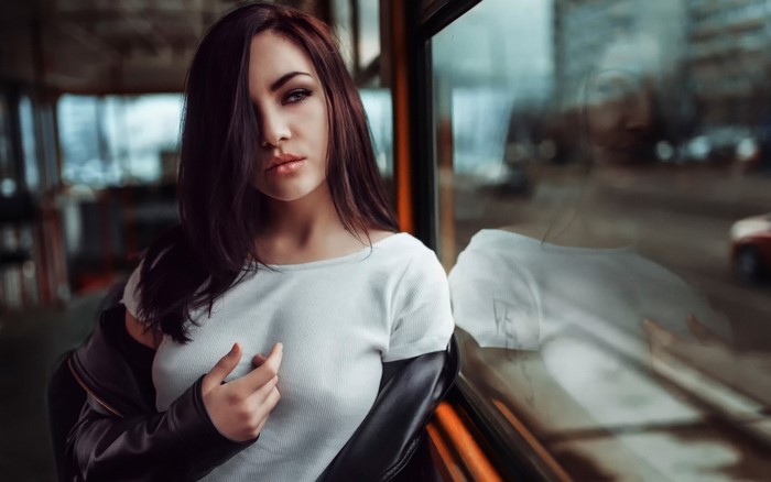 Woman in white top and black jacket by the window