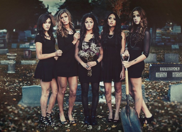 Five women in black dresses in a cemetery