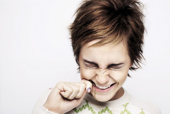 Emma Watson with short brown hair pulling on necklace