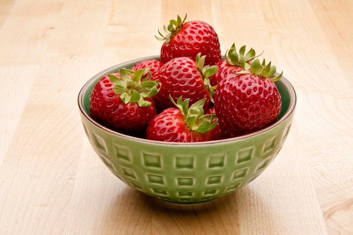 Bowl of fresh strawberries on a wooden table