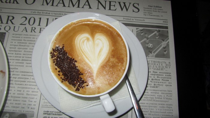 Cappuccino with heart art and chocolate sprinkles on newspaper