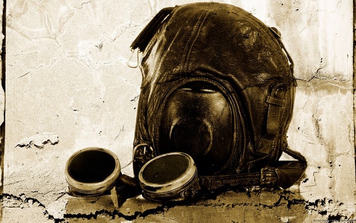 Vintage leather aviator helmet and goggles on a textured wall