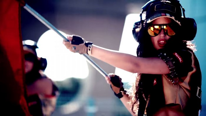 Woman in racing gear with headphones and sunglasses