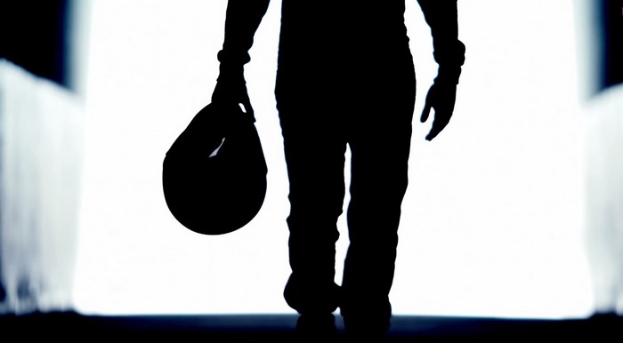 Silhouette of a person holding a helmet
