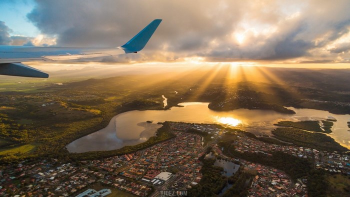 Airplane wing over coastal town at sunset