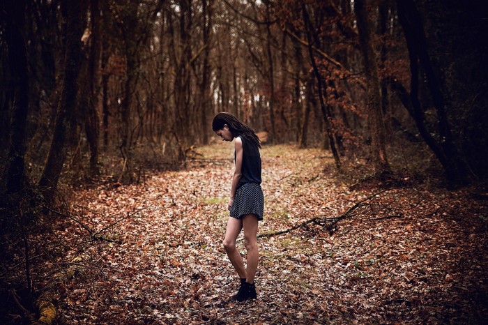 Woman in a dark forest with fallen leaves