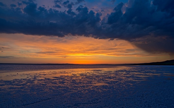 Sunset over a body of water with dark clouds