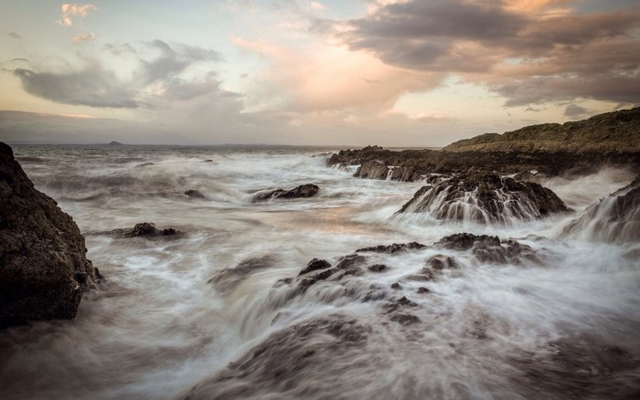 Ocean waves crashing on rocky shore at dawn