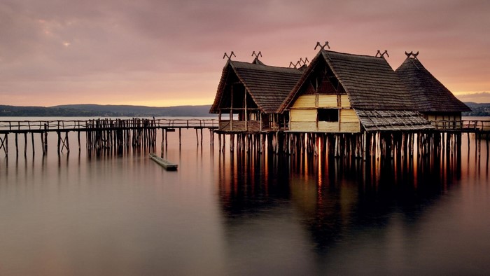 Stilt houses on a lake at sunset with a pier