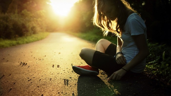 Woman sitting on a road during sunset