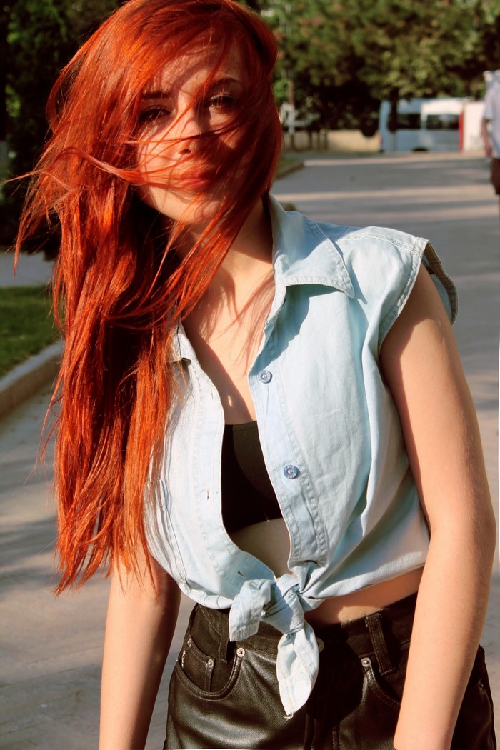 Redhead woman with hair in face wearing denim shirt