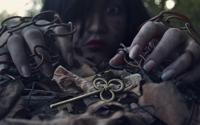 Woman with chains and key in leaves