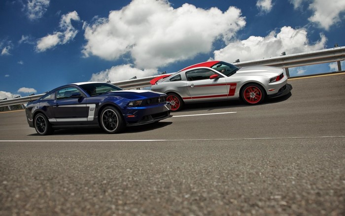 Two Ford Mustang Boss 302 cars on a road