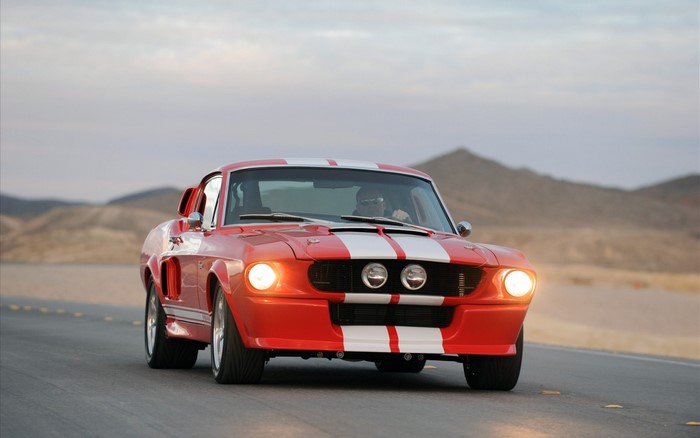 Red Ford Mustang Shelby GT500 driving on a road
