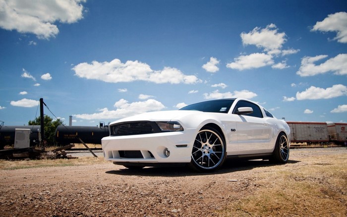 White Ford Mustang GT parked by train tracks