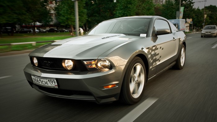 Gray Ford Mustang GT driving on a road