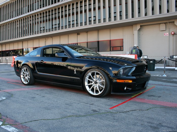 Black Ford Mustang Shelby GT500 parked in front of a building