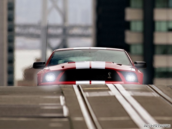Red Ford Mustang Shelby Cobra driving on a ramp