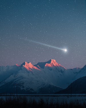 Shooting star over snow-capped mountains at dusk