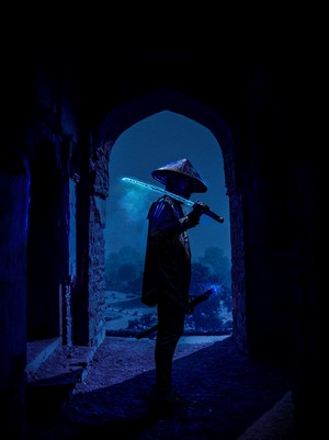 Samurai with glowing sword in ancient ruins at night