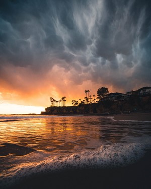 Sunset over a beach with palm trees and waves