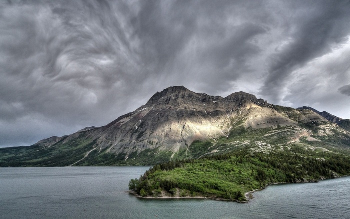 Mountain range overlooking a lake under cloudy skies