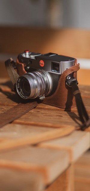 Leica camera with leather case on wooden table